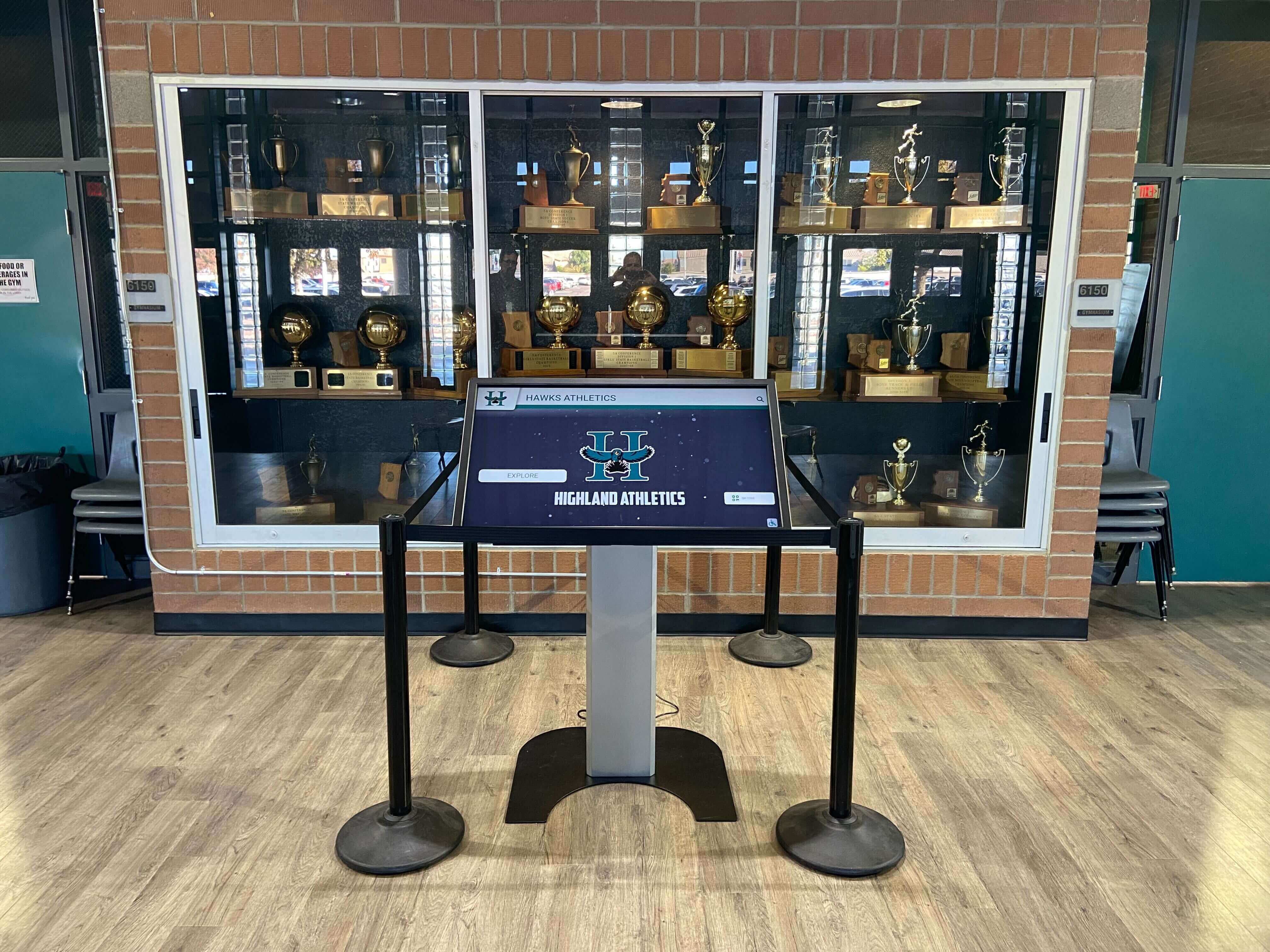 Touchscreen kiosk integrated into traditional athletic trophy display area Athletic display with touchscreen