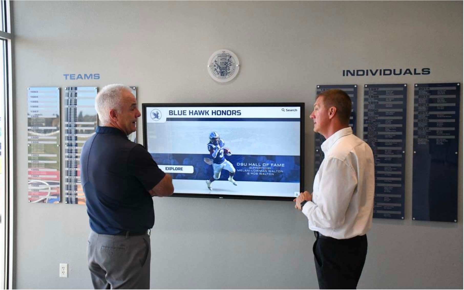 Two men viewing and discussing digital memorial hall of fame display
